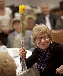 elderly woman holding up flower